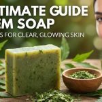 A bar of natural green neem soap resting on a wooden dish next to fresh neem leaves.