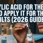 A woman applying a clear drop of salicylic acid serum to her cheek to treat acne breakouts.