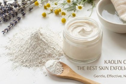 A bowl of pure white Kaolin clay powder next to a natural face mask applicator brush and fresh green leaves.