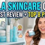 A collection of Tula Skincare products including the blue purifying face cleanser, eye balms, and moisture cream on a white marble surface.